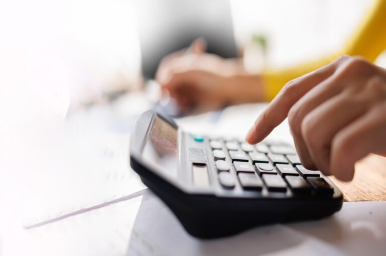 A person using a calculator while reviewing paperwork.